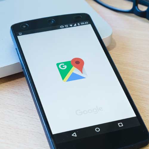 Ein Smartphone, das den Ladebildschirm der Google Maps-App anzeigt, liegt auf einem Holztisch - perfekt für die Verwaltung lokaler SEO- oder Optimierungsstrategien für das Google-Ranking.